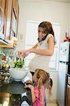 Femme en utilisant le téléphone et la préparation de salade avec fille