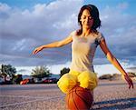 Young woman kneeling on basketball