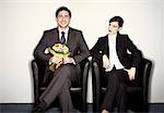 Male office worker with flowers sitting next to female colleague