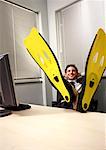 Employé de bureau devant un ordinateur portant des palmes de natation