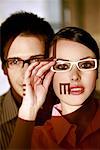 Frau mit Brille mit optischen Prüfung Zeichen auf ihrem Gesicht und der Mann hinter