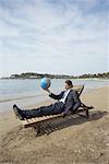 Businessman on chaise lounge with globe