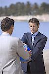 Businessmen on beach holding globe