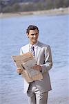 Businessman on beach holding a newspaper