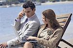 Business couple on beach with cell phone and laptop