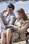 Business couple on beach with cell phone and laptop