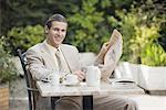 Businessman in garden cafe with newspaper