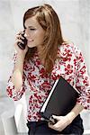 Femme d'affaires sur téléphone cellulaire tenant un liant