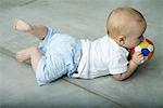 Baby lying on floor, biting on ball