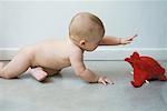 Baby on floor reaching for elephant puppet