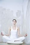 Young woman sitting in lotus position, eyes closed, full length