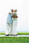 Senior couple dancing on sidewalk overlooking ocean, full length, blurred motion