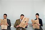 Three businesspeople reading newspaper