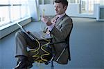 Businessman with laptop on lap holding an network cable
