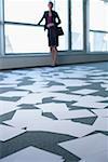 Businessman standing in an empty office, sheets of paper on floor