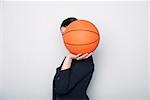 Businesswoman covering face with a basketball