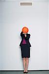 Businesswoman covering face with a basketball