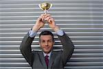 Businessman holding a trophy above head