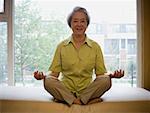 Mature woman sitting cross legged in meditation smiling