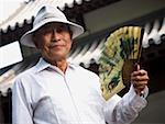 Mature man holding fan and smiling with motion blur