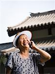 Frau mit Sonnenblende im freien lächelnd am Handy sprechen