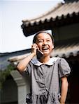 Girl standing outdoors with cell phone in front of pagoda smiling