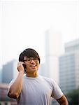 Homme avec des lunettes parlait au téléphone cellulaire souriant à l'extérieur