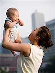 Woman lifting baby outdoors and smiling