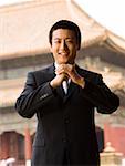 Businessman smiling with hands in greeting with pagoda in background