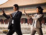 Businesswoman and man doing tai chi outdoors