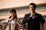 Businesswoman and man doing tai chi outdoors smiling