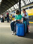 Enfants en attente avec des bagages à la gare