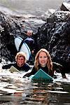 Trois personnes avec des planches de surf souriant.