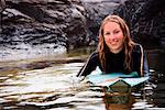 Frau liegend auf Surfbrett in die Wasser-Lächeln.