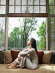 Woman with eyes closed sitting on sofa in living room.