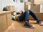 Couple sleeping on floor with moving boxes around them.