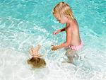 Young boy playing with a doll in a pool.