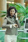 Femme d'affaires parlant sur un téléphone payant et en vérifiant l'heure