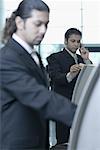 Two businessmen using express check-in service at an airport