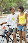 Jeune couple debout avec une bicyclette et souriant