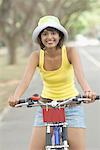 Portrait d'une jeune femme enfourcher une bicyclette et souriant