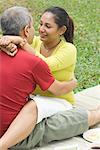 Mid adult couple sitting in a park and embracing each other