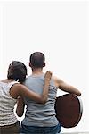 Rear view of a young man sitting with his friend and playing a guitar