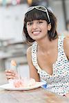 Portrait d'une jeune femme, manger des salades de fruits et souriant