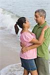 Side profile of a mid adult couple embracing each other on the beach