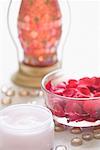 Close-up of rose petals in a bowl with moisturizer and a lantern