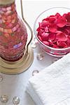 Close-up of rose petals in a bowl with a stack of towels and a lantern