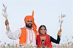 Portrait d'un jeune couple debout dans un champ de blé et la tenue des cultures