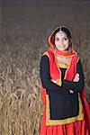 Portrait of a young woman standing in a wheat field and smiling