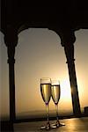 Close-up of two champagne flutes under a gazebo at sunset